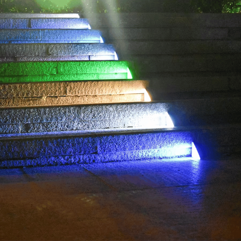 Multi-color LED Stair Lamps lighting up stone steps in a garden at night
